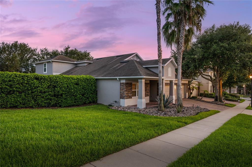 A single-story house with a stone facade, a paved driveway, and a manicured lawn — 15604 GRANLUND STREET, WINTER GARDEN, FL