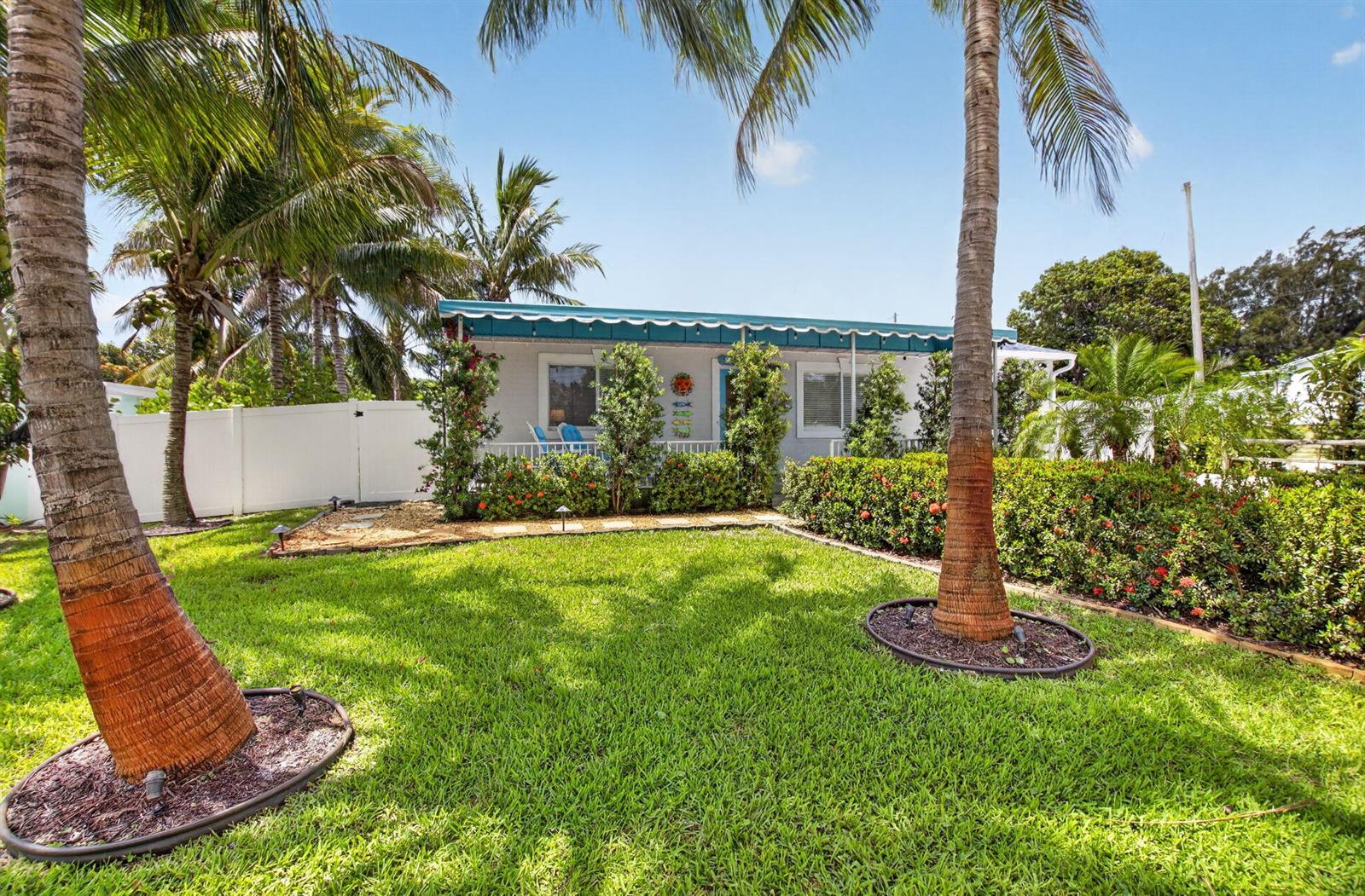 A small, light-colored house with a blue awning sits behind a lawn and palm trees — 468 W Ocean Avenue, Boynton Beach FL 33435, BOYNTON BEACH, FL