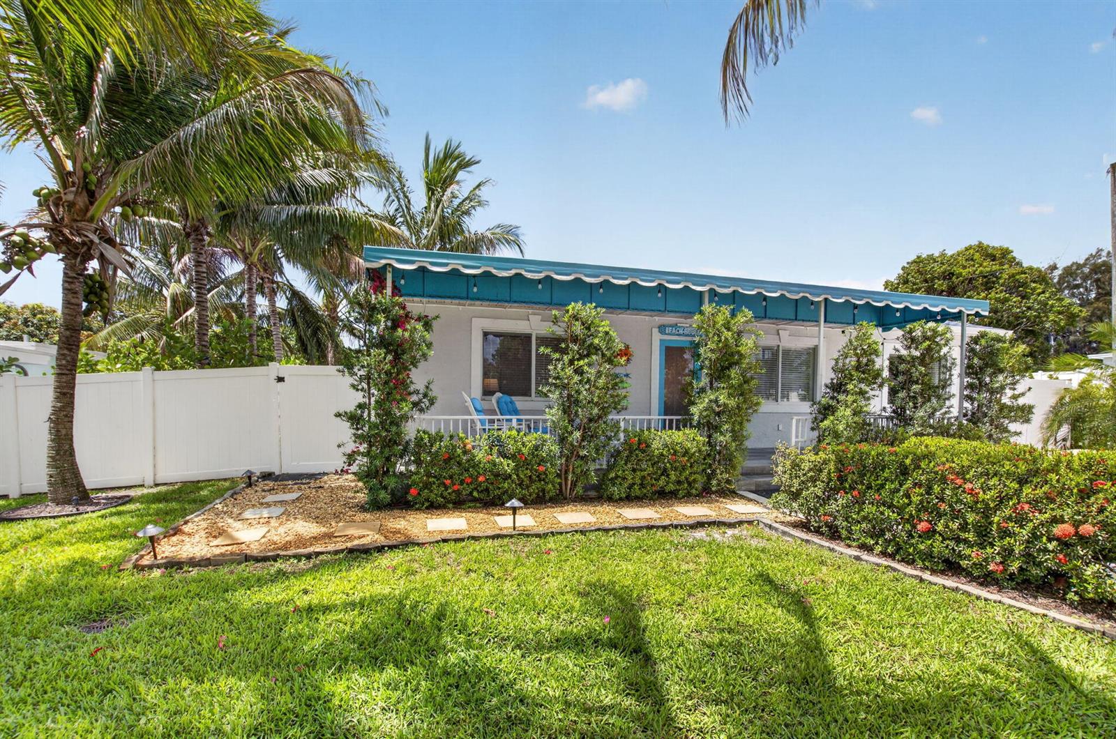 A single-story house with a blue awning and porch sits behind a landscaped front yard — 468 W Ocean Avenue, Boynton Beach FL 33435, BOYNTON BEACH, FL