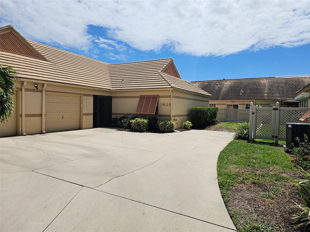 A beige single-story house with a concrete driveway and a tiled roof — 3625 57TH AVENUE DRIVE W, BRADENTON, FL