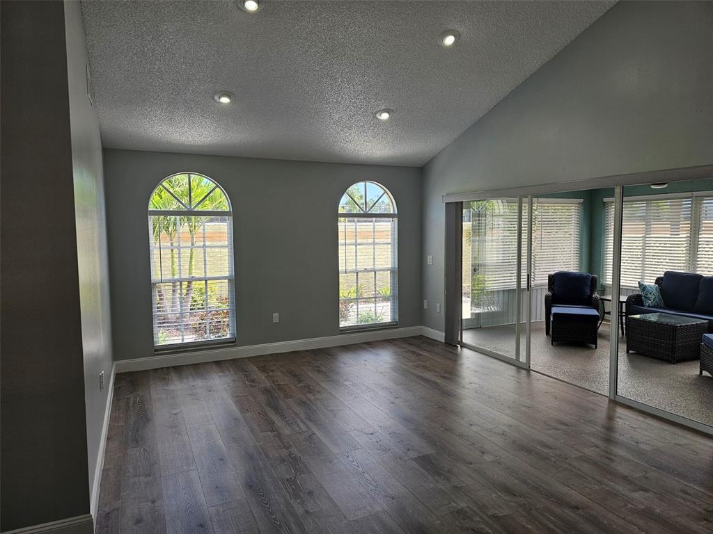 A living room features wood-look flooring, arched windows, recessed lighting, and a sliding glass door — 3625 57TH AVENUE DRIVE W, BRADENTON, FL