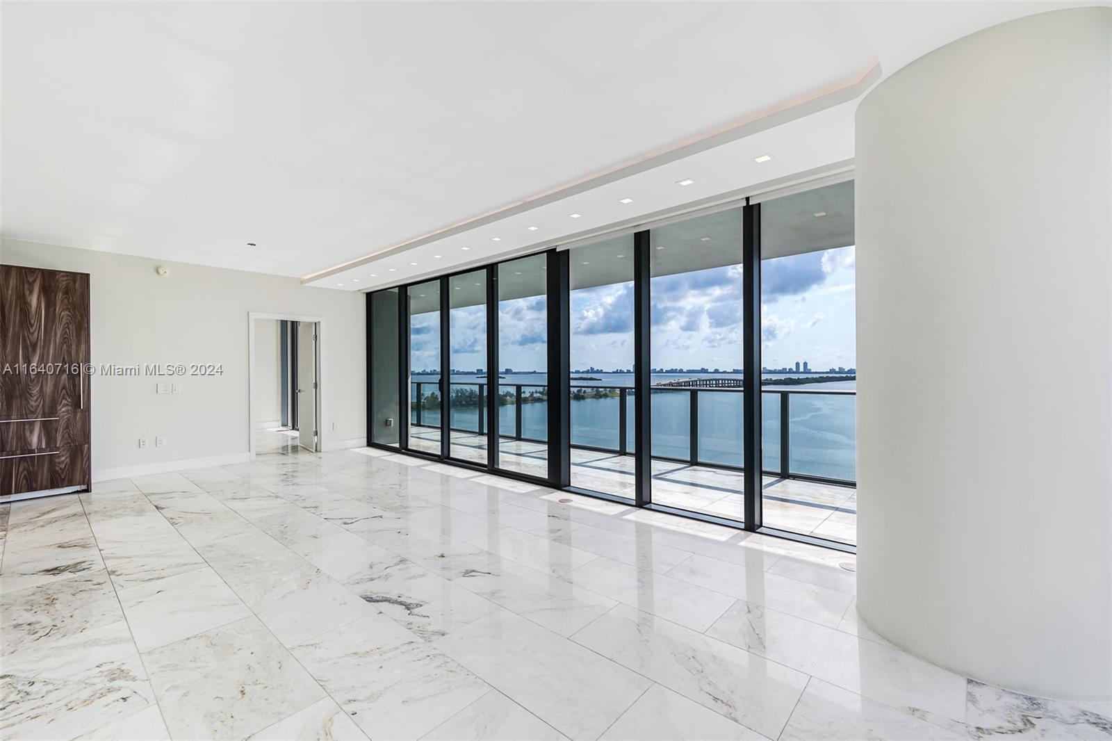 A bright, modern living room features white marble floors, floor-to-ceiling windows, and a water view — 3131 NE 7th Ave # 1101, Miami FL 33137, MIAMI, FL
