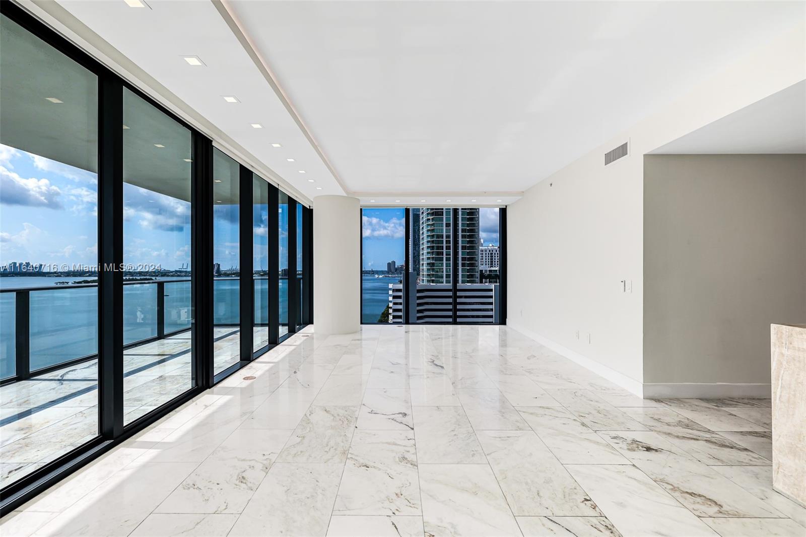 An empty room features white marble flooring, floor-to-ceiling windows, and a view of the water — 3131 NE 7th Ave # 1101, Miami FL 33137, MIAMI, FL