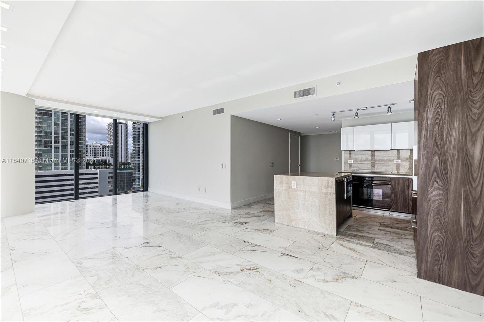 An open-concept living area features marble flooring, a modern kitchen island, and floor-to-ceiling windows — 3131 NE 7th Ave # 1101, Miami FL 33137, MIAMI, FL