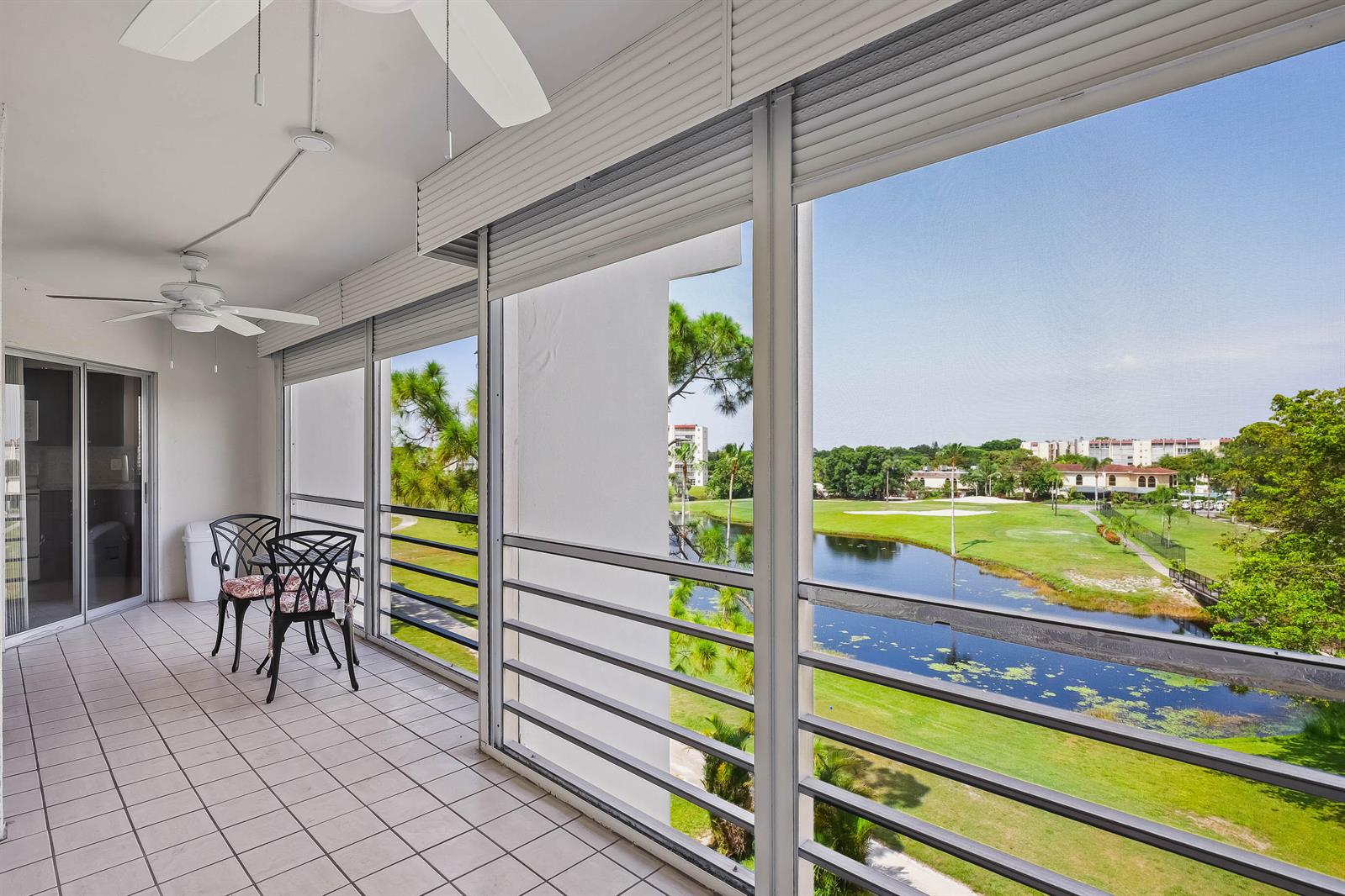 A tiled balcony features a seating area and views of a golf course and pond — 3593 Birdie Drive # 507, FL 33467, FL