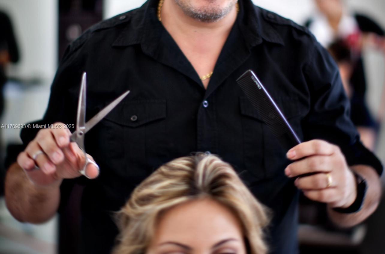 A hairstylist holds scissors and a comb while working on a client's blonde hair — NW 36 ST, Doral FL 33122, DORAL, FL