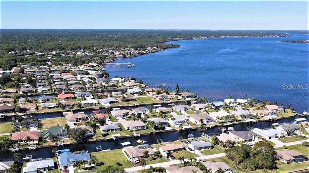 An aerial view shows a residential neighborhood with canals leading into a large lake — 12739 BACCHUS ROAD, PORT CHARLOTTE, FL