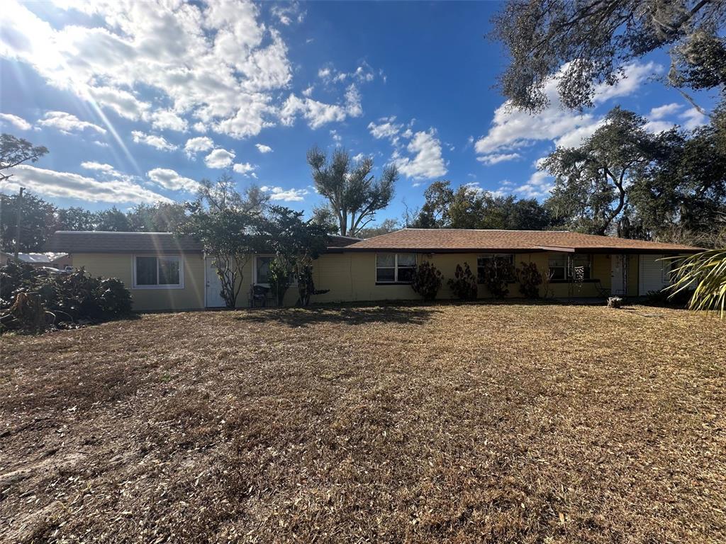A single-story yellow house with a brown roof sits behind a large, dry grassy yard — 2220 N GALLOWAY ROAD, LAKELAND, FL