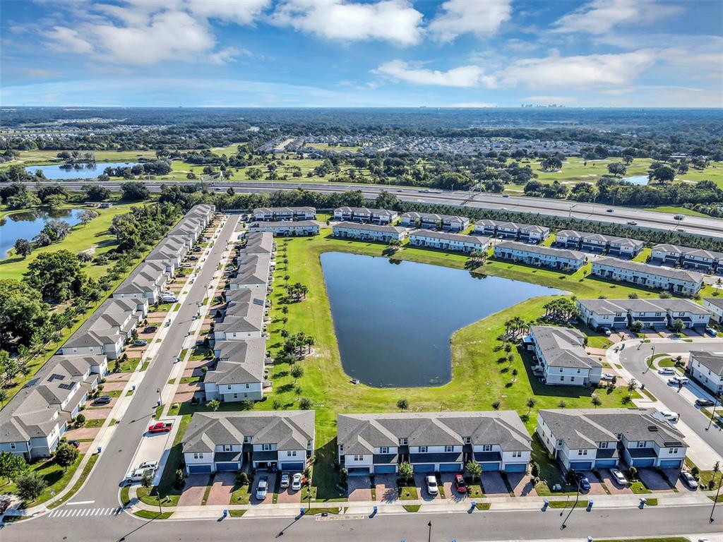 An aerial view shows a residential community of townhomes surrounding a central retention pond — 1073 DESERT CANDLE DRIVE, OCOEE, FL