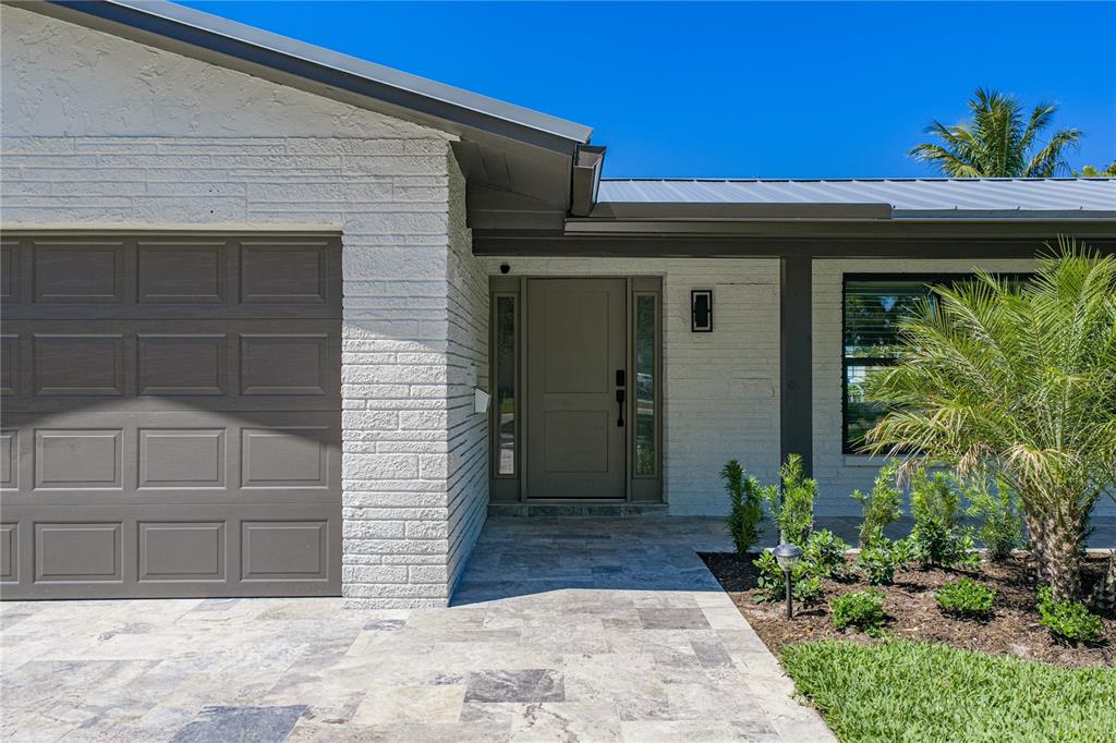 The exterior of a house features white painted brick, a gray garage door, and stone pavers — 4201 37TH STREET S, ST PETERSBURG, FL
