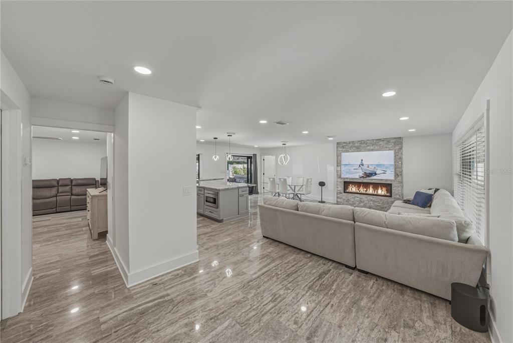 An open-concept living room and kitchen featuring light-colored tile flooring and a stone fireplace — 4201 37TH STREET S, ST PETERSBURG, FL