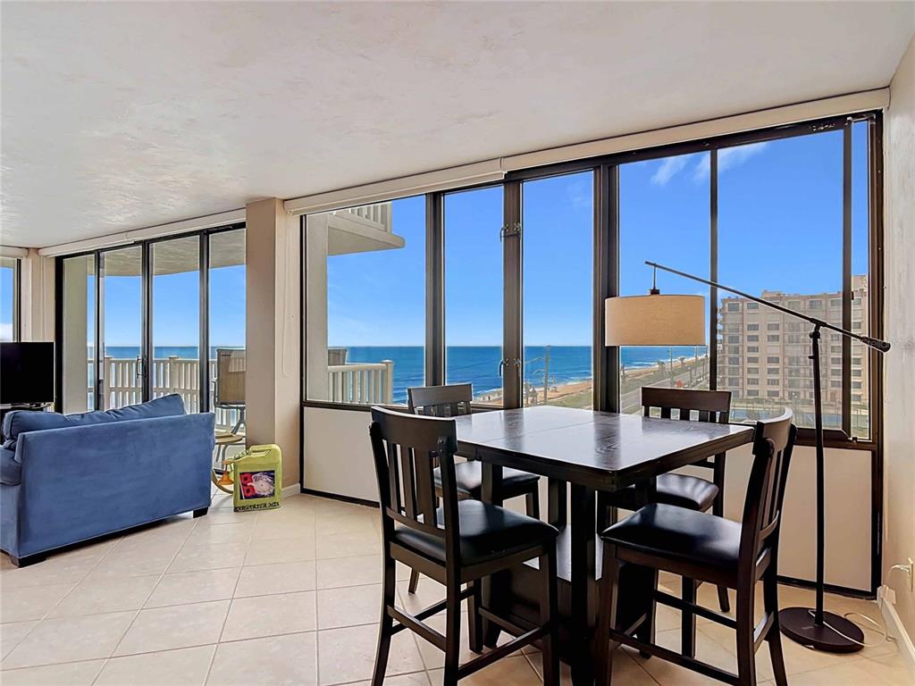 A dining area and living space with floor-to-ceiling windows overlooking the ocean — 3580 S OCEAN SHORE BOULEVARD UNIT 506, FLAGLER BEACH, FL