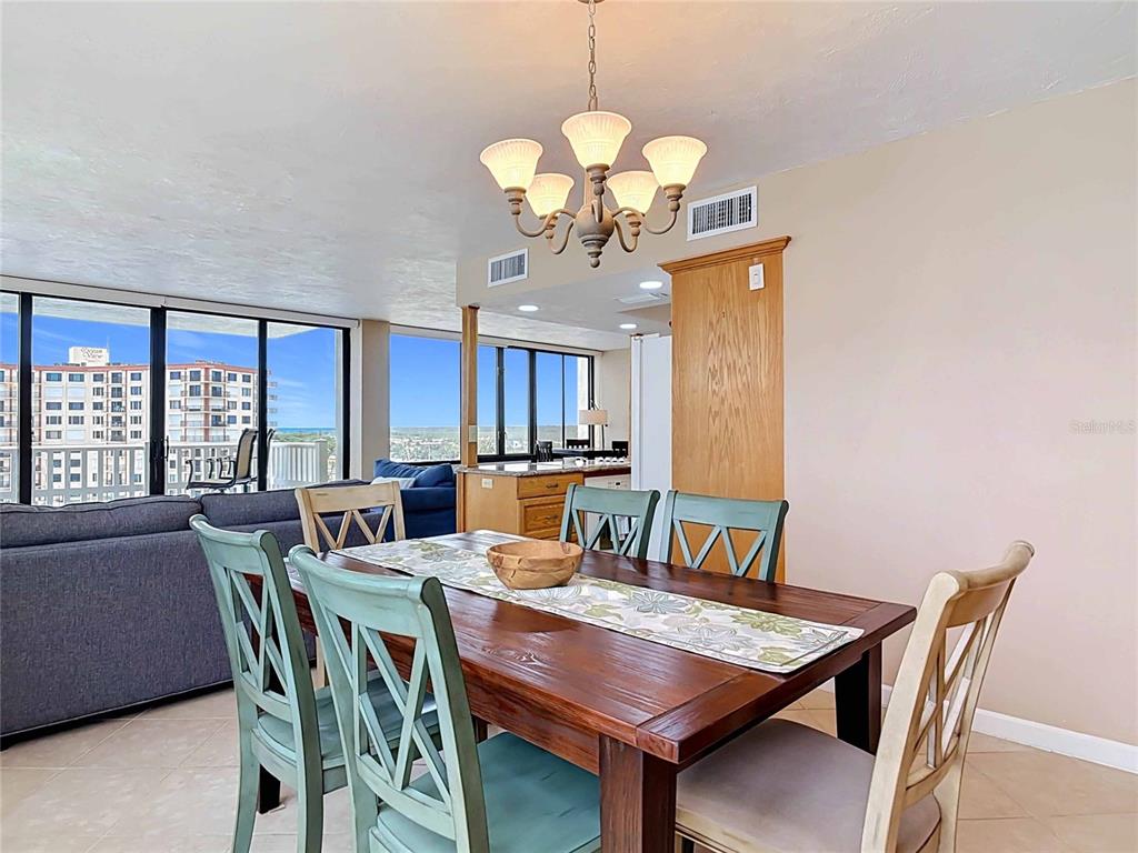 A dining area features a wooden table with mixed chairs under a chandelier near windows — 3580 S OCEAN SHORE BOULEVARD UNIT 506, FLAGLER BEACH, FL