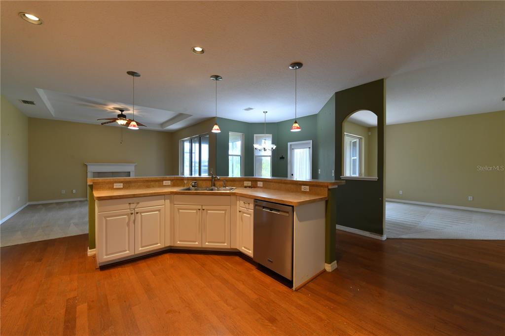 A kitchen with white cabinets, laminate countertops, and hardwood floors overlooks an open living area — 2509 155TH AVENUE E, PARRISH, FL