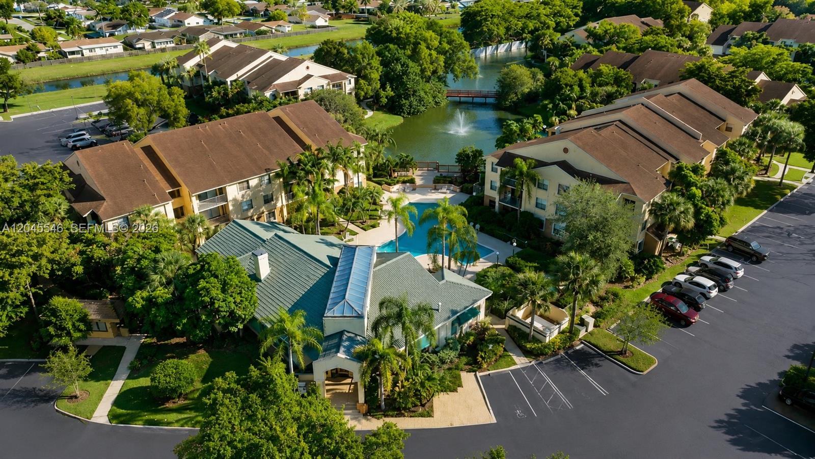 An aerial view shows a residential complex with a swimming pool, pond, and parking lots — 9999 Summerbreeze Dr # 317, Sunrise FL 33322, SUNRISE, FL