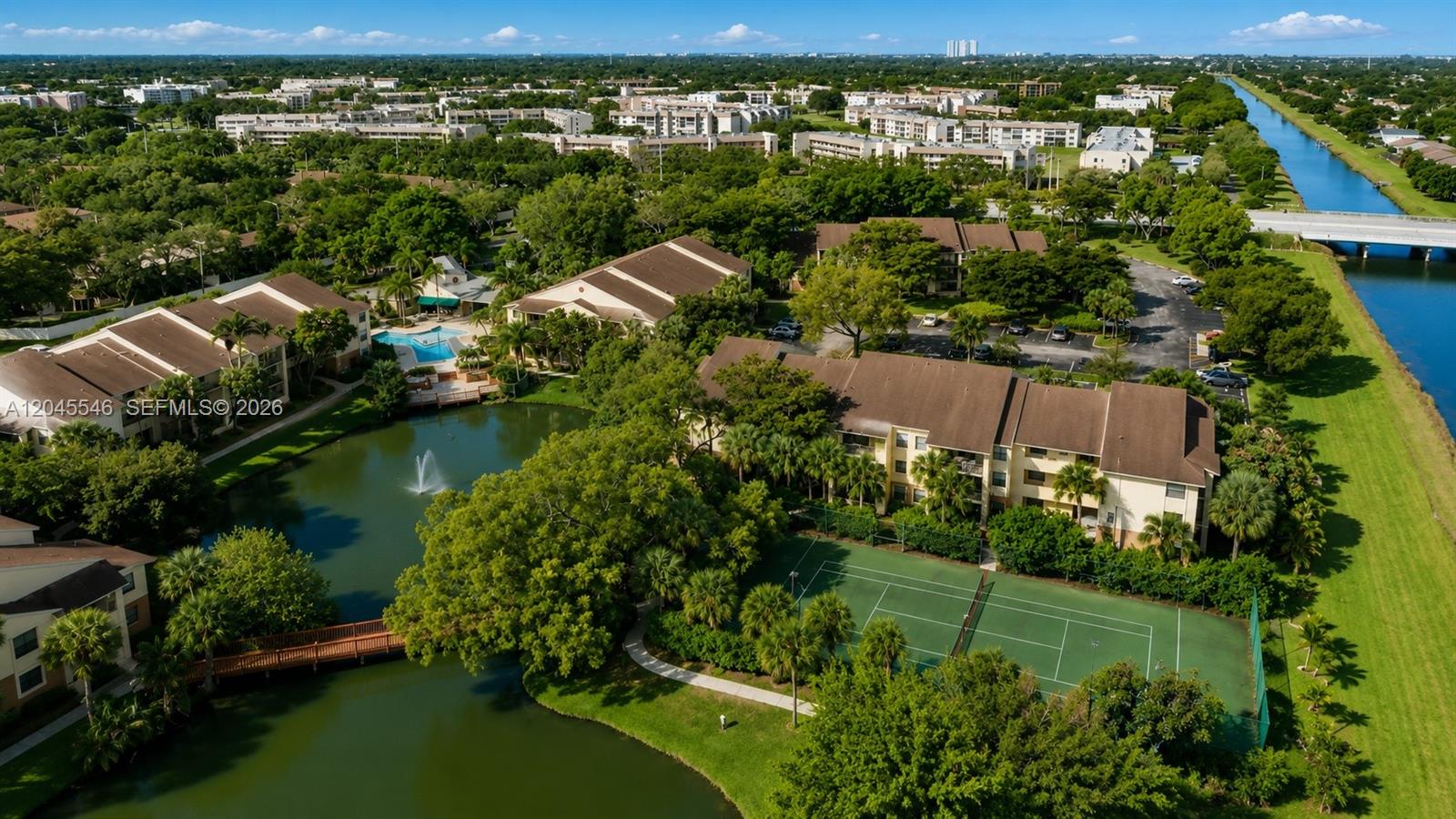 An aerial view shows apartment buildings, a swimming pool, a tennis court, and a canal — 9999 Summerbreeze Dr # 317, Sunrise FL 33322, SUNRISE, FL