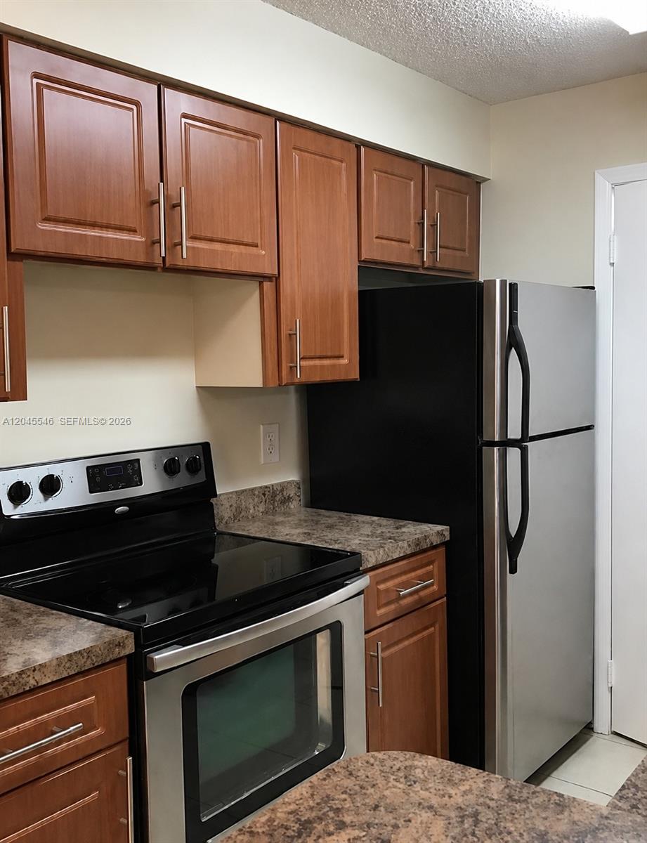 A kitchen features wood cabinets, stainless steel appliances, and brown laminate countertops — 9999 Summerbreeze Dr # 317, Sunrise FL 33322, SUNRISE, FL