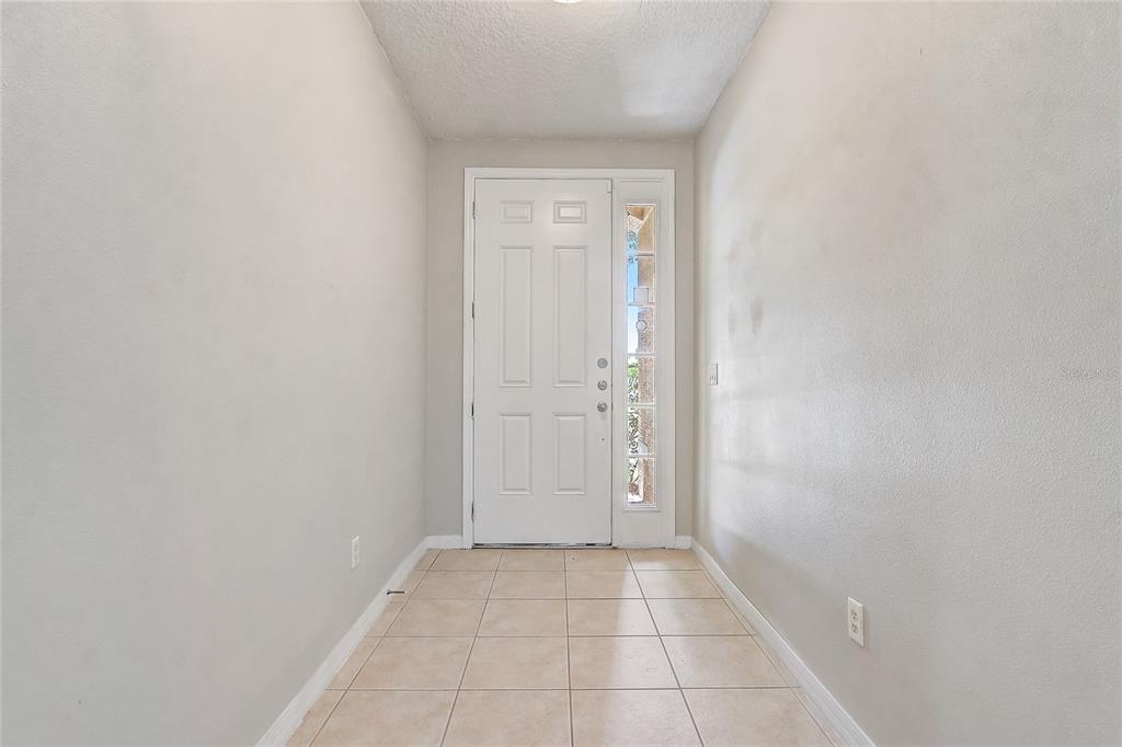An entryway with beige tile flooring, light-colored walls, and a white front door with sidelights — 3028 CAMINO REAL DRIVE S, KISSIMMEE, FL