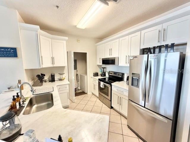 A kitchen features white cabinetry, stainless steel appliances, and a marble-patterned countertop — 1408 LAKE SHADOW CIRCLE UNIT 1308, MAITLAND, FL