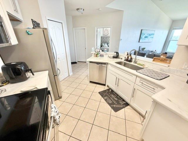 A kitchen features white cabinets, stainless steel appliances, and light-colored tile flooring — 1408 LAKE SHADOW CIRCLE UNIT 1308, MAITLAND, FL