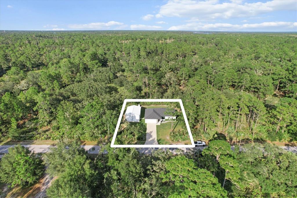 An aerial view shows a house and detached garage on a wooded lot — 11855 W FLAXEN DRIVE, CRYSTAL RIVER, FL