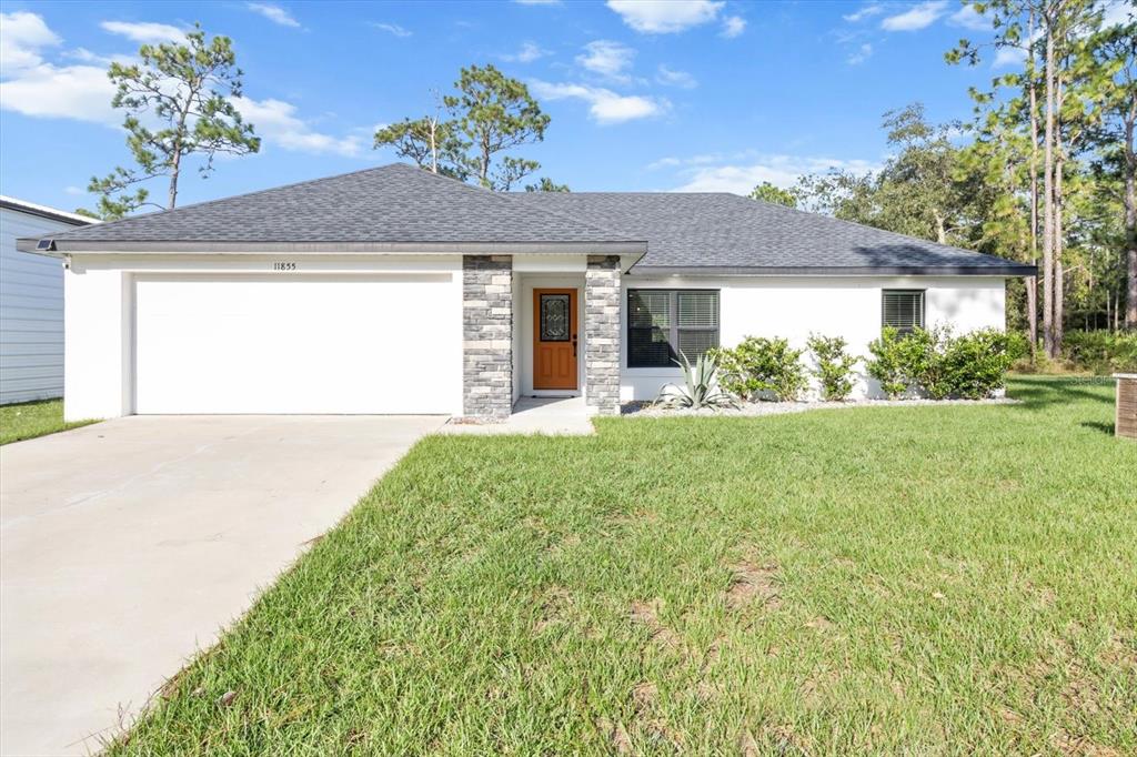 A single-story house with a white exterior, stone accents, and a two-car garage — 11855 W FLAXEN DRIVE, CRYSTAL RIVER, FL