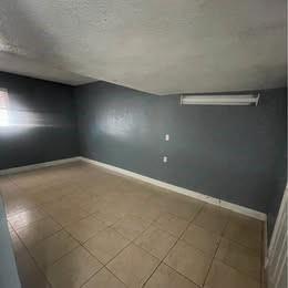 An empty room features dark gray walls, light-colored tile flooring, and a ceiling-mounted light fixture — 12030 NW 29th Manor, Sunrise FL 33323, SUNRISE, FL