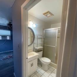 A bathroom features a vanity with a round mirror, a toilet, and a glass shower stall — 12030 NW 29th Manor, Sunrise FL 33323, SUNRISE, FL