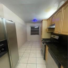 A galley kitchen features light wood cabinets, black countertops, stainless steel appliances, and tiled flooring — 12030 NW 29th Manor, Sunrise FL 33323, SUNRISE, FL