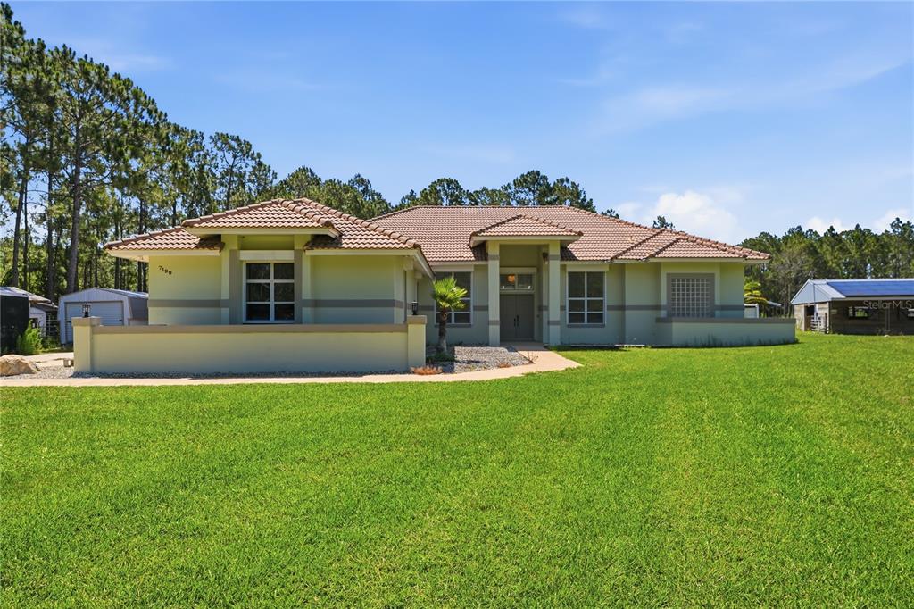 A single-story house with a tiled roof and light green exterior sits on a lawn — 7190 SIX GUN COURT, ST CLOUD, FL