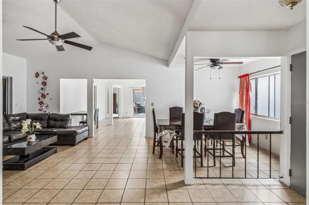An open-concept living and dining area features vaulted ceilings, tile flooring, and a ceiling fan — 271 MARIPOSA, WINTER HAVEN, FL