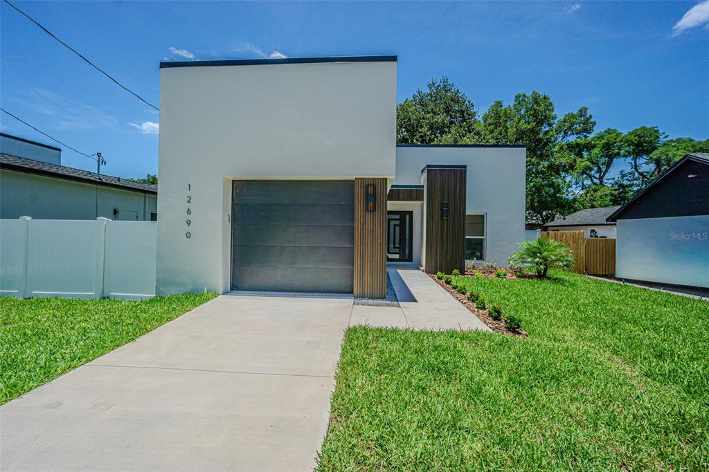 A modern single-story house with a flat roof, a garage, and a concrete driveway — 12690 N CENTRAL AVENUE, TAMPA, FL