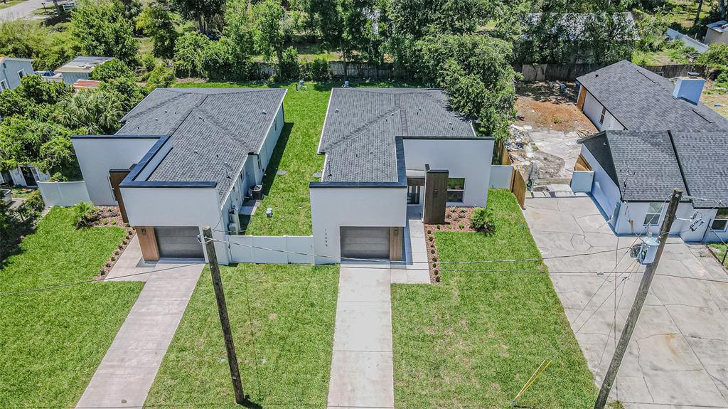 An aerial view shows two modern, flat-roofed houses with garages and concrete driveways — 12690 N CENTRAL AVENUE, TAMPA, FL
