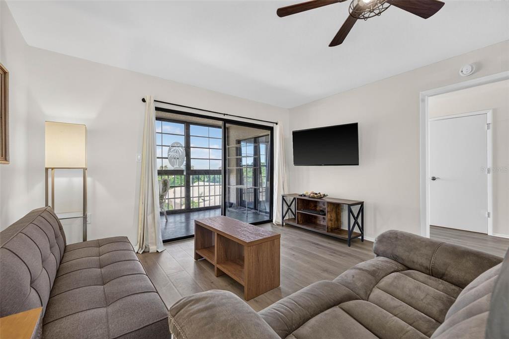 A living room features two gray sofas, a wood coffee table, and a sliding glass door — 9860 62ND TERRACE N UNIT 1048, ST PETERSBURG, FL