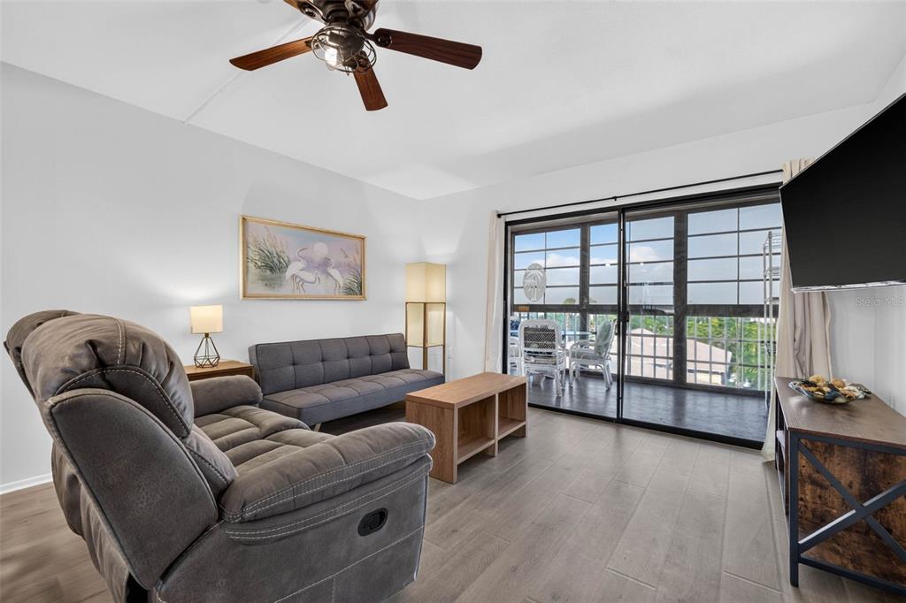 A living room features gray flooring, a recliner, a sofa, and a sliding glass door — 9860 62ND TERRACE N UNIT 1048, ST PETERSBURG, FL