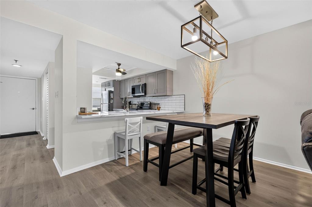 A dining area with a wooden table and chairs sits adjacent to a modern kitchen — 9860 62ND TERRACE N UNIT 1048, ST PETERSBURG, FL