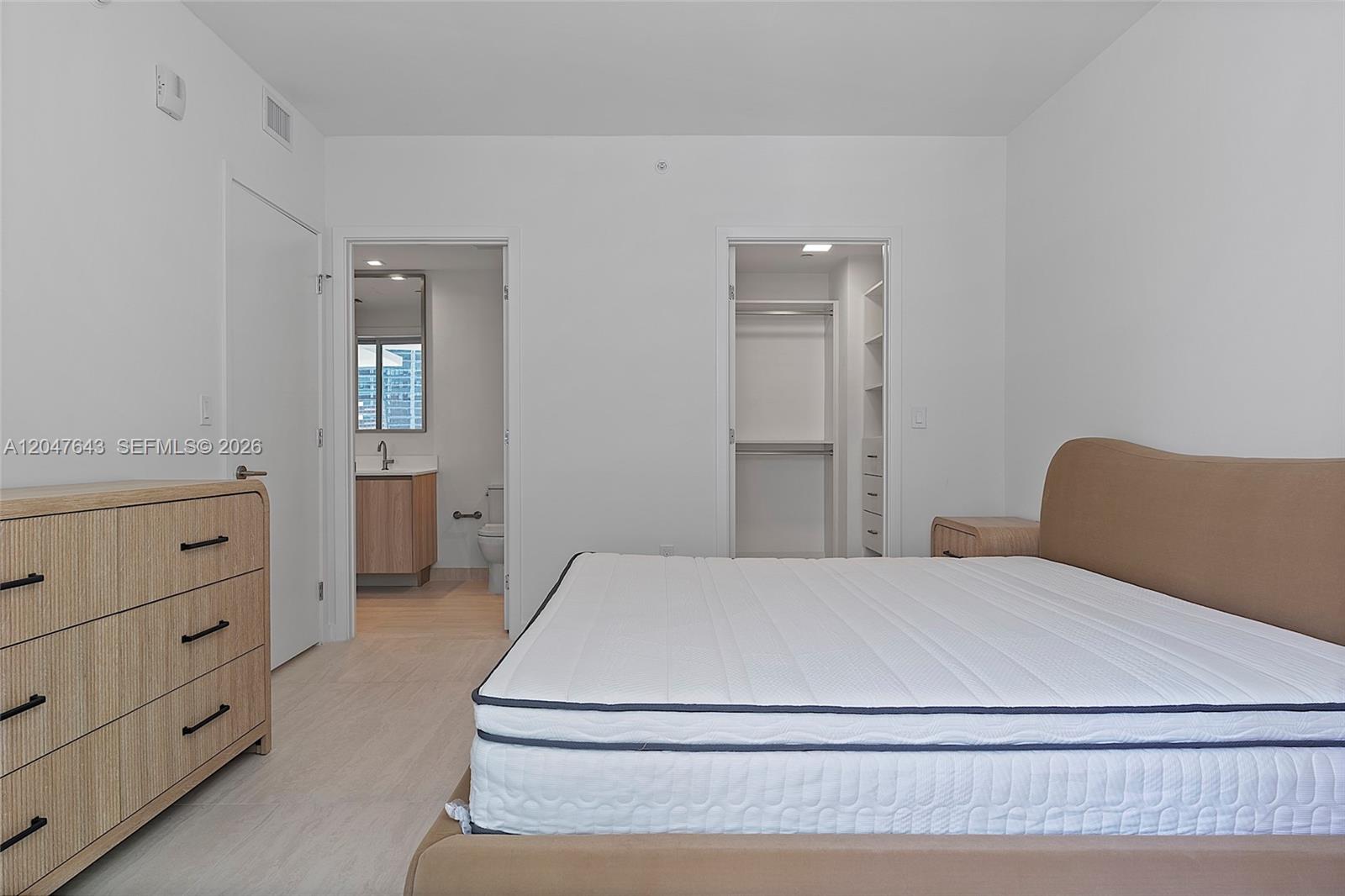 A bedroom features a bed, a dresser, an attached bathroom, and a walk-in closet — 77 SE 5th St. # 1905, Miami FL 33131, MIAMI, FL