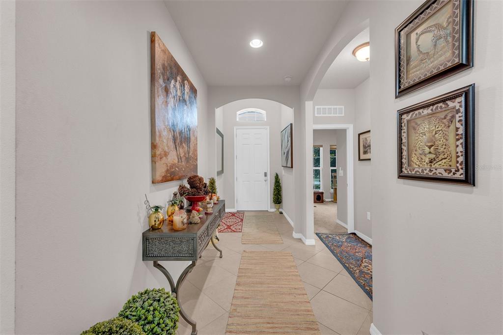 A tiled entryway features a console table, wall art, and a white front door — 980 GLAZEBROOK LOOP, ORANGE CITY, FL