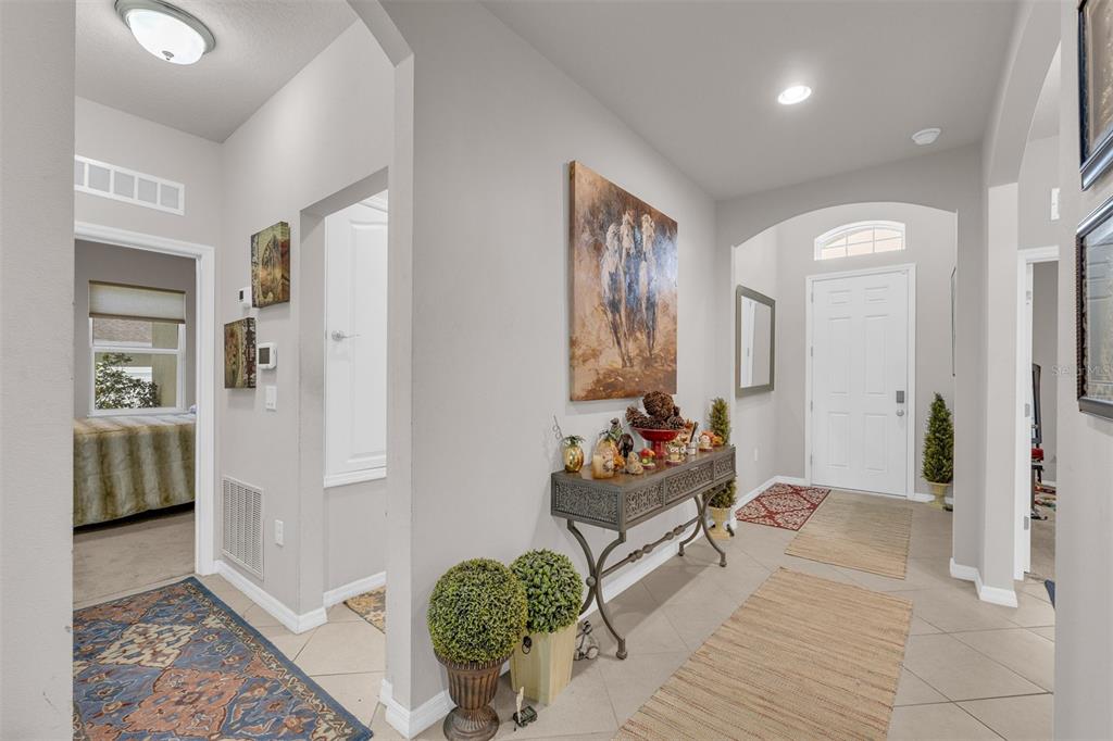 A tiled entryway features a console table, wall art, and a view into a bedroom — 980 GLAZEBROOK LOOP, ORANGE CITY, FL