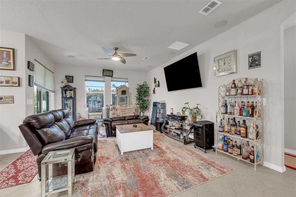 A living room features a leather sofa, a coffee table, a television, and a liquor shelf — 980 GLAZEBROOK LOOP, ORANGE CITY, FL