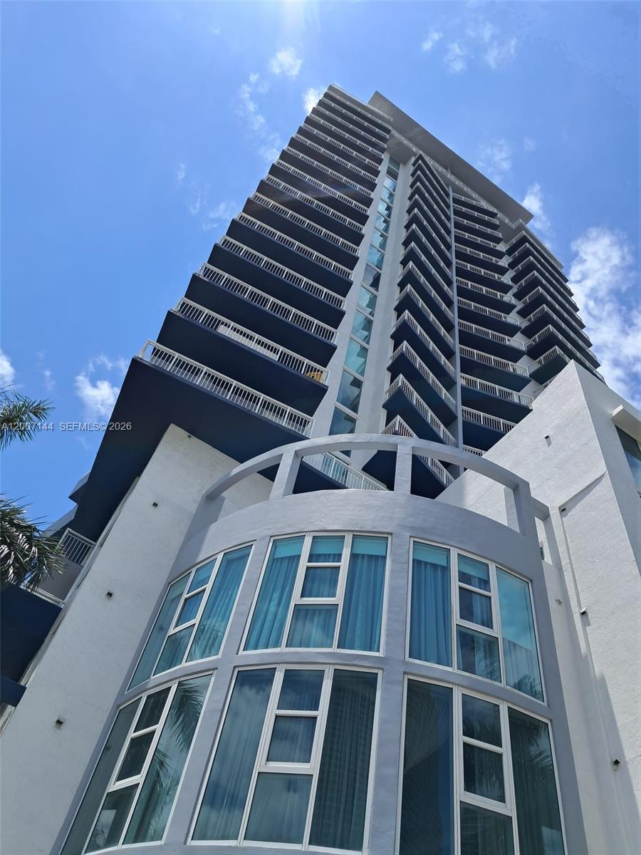A low-angle view shows the exterior of a tall, modern high-rise residential building — 275 NE 18th St # 1704, Miami FL 33132, MIAMI, FL