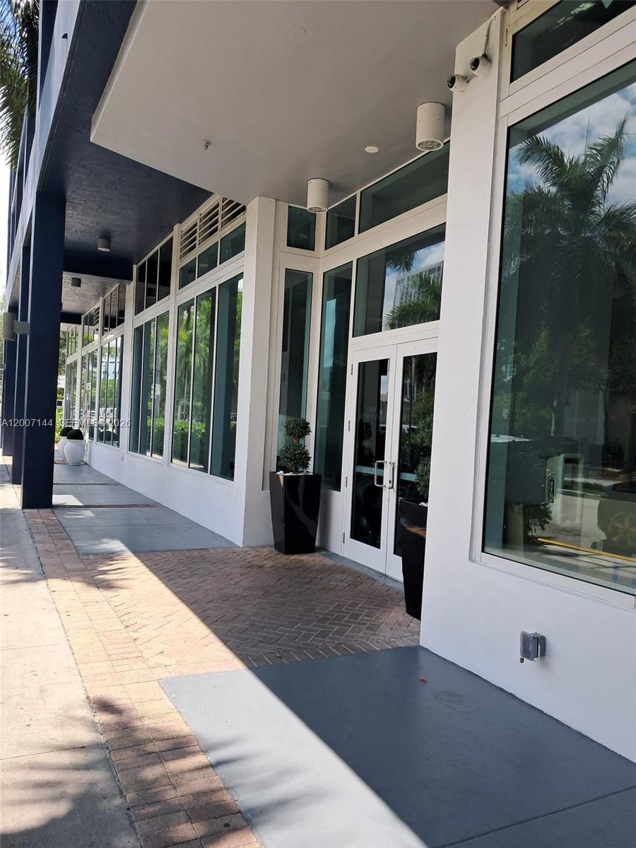 The exterior of a building features a brick walkway, glass doors, and large windows — 275 NE 18th St # 1704, Miami FL 33132, MIAMI, FL