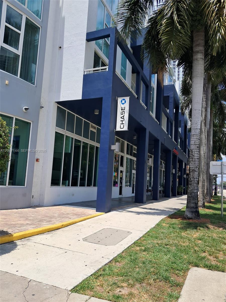 A street-level view of a modern building featuring a Chase bank branch and palm trees — 275 NE 18th St # 1704, Miami FL 33132, MIAMI, FL