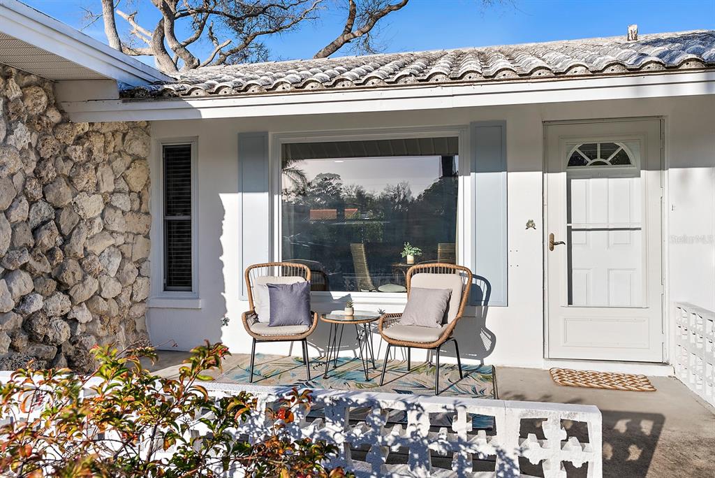 A patio with two chairs and a small table sits in front of a house — 514 HARBOR DRIVE S, VENICE, FL