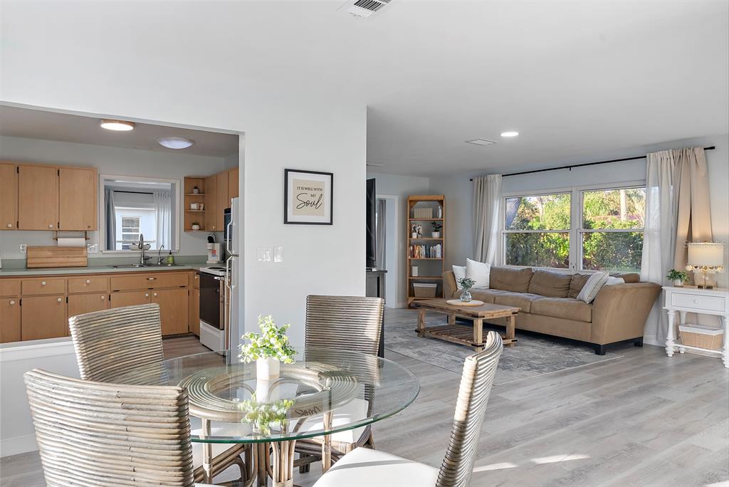 An open-concept living room and kitchen with light wood cabinets and a glass dining table — 514 HARBOR DRIVE S, VENICE, FL