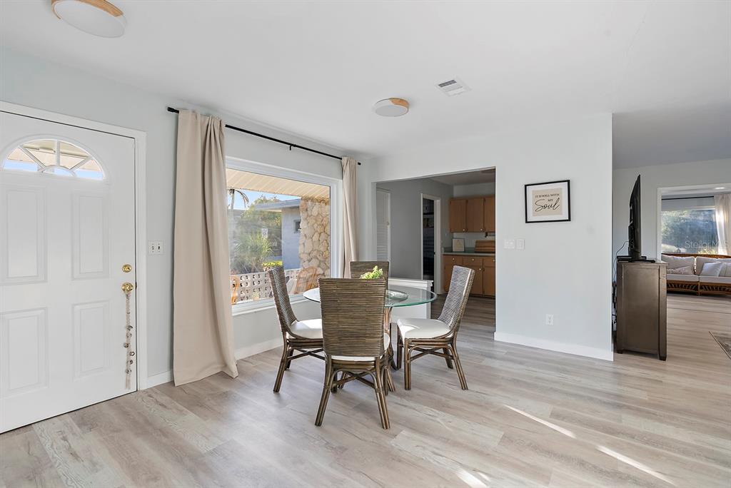A dining area with a glass table, wicker chairs, and light wood-look flooring — 514 HARBOR DRIVE S, VENICE, FL