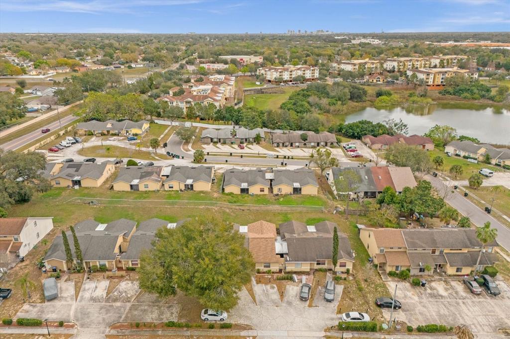 An aerial view shows multiple rows of townhouses with parking spaces and a nearby pond — 1267 WOODMAN WAY, ORLANDO, FL