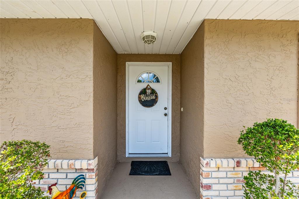 A white front door with a "Blessed" sign is set within a tan stucco entryway — 5 SILVER RUN, OCALA, FL
