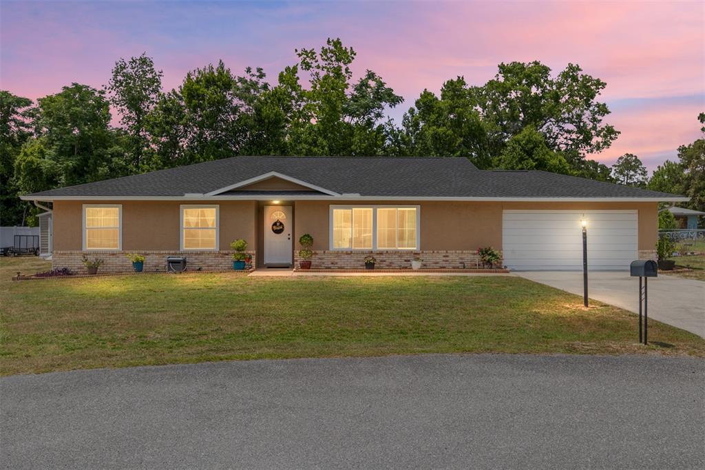 A single-story house with a tan stucco exterior, brick trim, and a two-car garage — 5 SILVER RUN, OCALA, FL