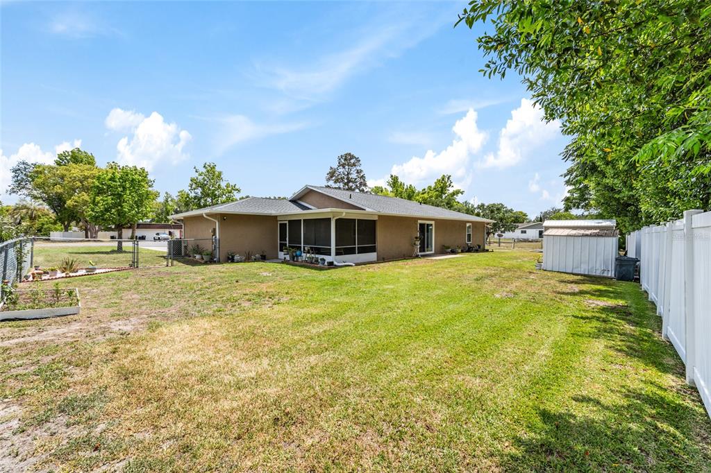 A tan house with a screened-in porch sits in a large, grassy backyard — 5 SILVER RUN, OCALA, FL